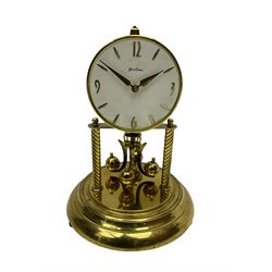 A mid-20th century “Bentima” 400-day anniversary torsion clock with a 7” circular brass base and unenclosed movement supported on two twisted columns, with a white dial gilt numerals and baton hands, four-ball rotary pendulum and glass dome. 


