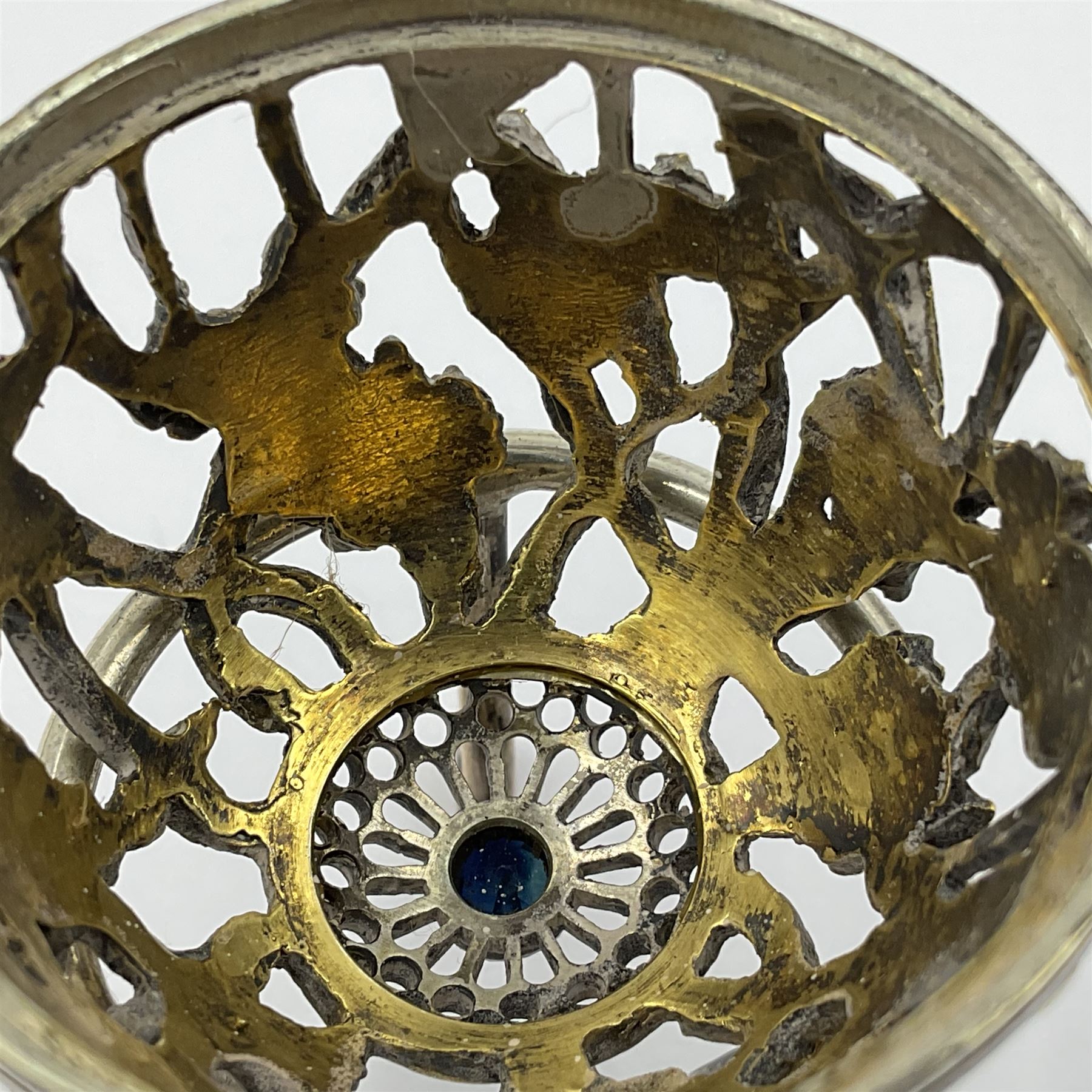 Modern silver limited edition Easter egg, no. 70/500, the gilt openwork body decorated with daffodils and detachable cover with pierced circular panel set with a single faceted blue stone, opening to reveal a gilt interior, upon silver stand with three scrolling pad feet, each hallmarked St James House Company, London 1980, height including stand 8cm