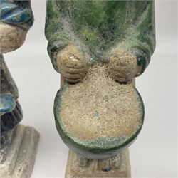 Three Chinese terracotta court attendant tomb figures, probably Ming Dynasty, two examples decorated in Sancai green glaze, the third example decorated in two tone blue glaze, each upon stepped square bases, tallest H22.7cm