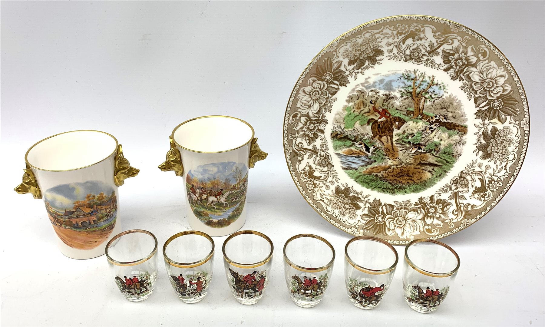  A collection of hunting related items, comprising a pair of Caverswall beakers, each with twin gilt fox head handles, H11.5cm, a limited edition Spode cabinet place depicting 'Drawing the Dingle' after J F Herring Sen, D24cm, and a set of six French shot glasses, decorated with huntsmen on horseback and hounds, H5.5cm.  