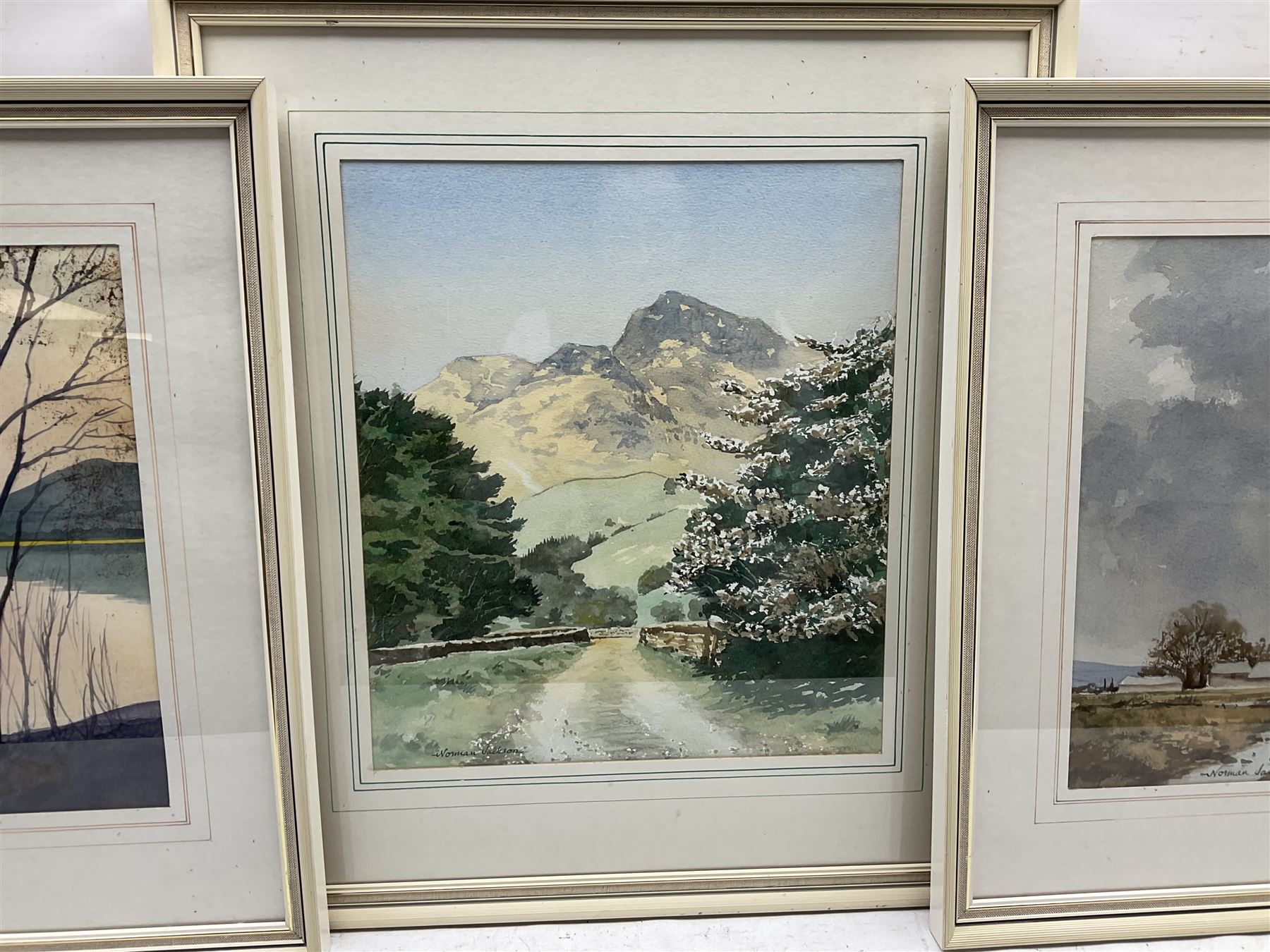 Norman Jackson (British 20th century): Sunset Lake Landscape and Flatland Landscape with Hilly Scene, pair watercolours together with a smaller by the same hand, signed max 31cm x 51cm (3)