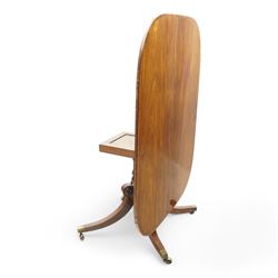 Regency figured mahogany breakfast table, figured rectangular tilt-top with rounded corners and rosewood banding, on turned column with four out-splayed supports with brass cups and castors 
