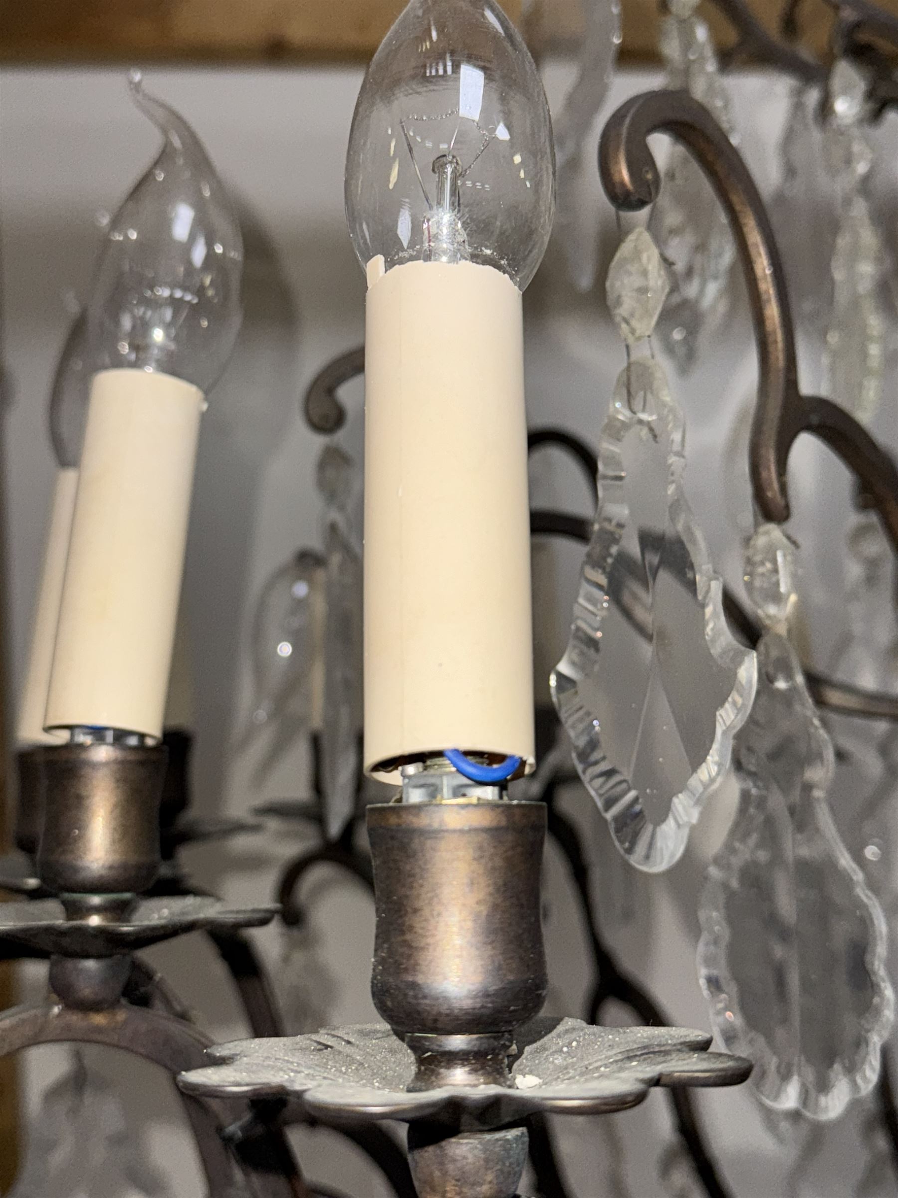 Early 20th century continental cut glass and metal chandelier, with sixteen candle style lights on a single tier of scrolled arms, hung with faceted glass drops and centred by a mould-blown and cut glass baluster stem, suspended from a ceiling rose and chain