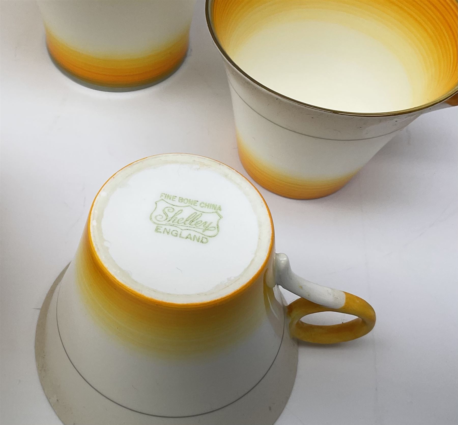 A Shelley Art Deco tea service, decorated in pattern no W12405, with bands of grey, orange and yellow, comprising teapot, open sucrier, milk jug, cake plate, six teacups, six saucers, six side plates, and six dessert plates. 