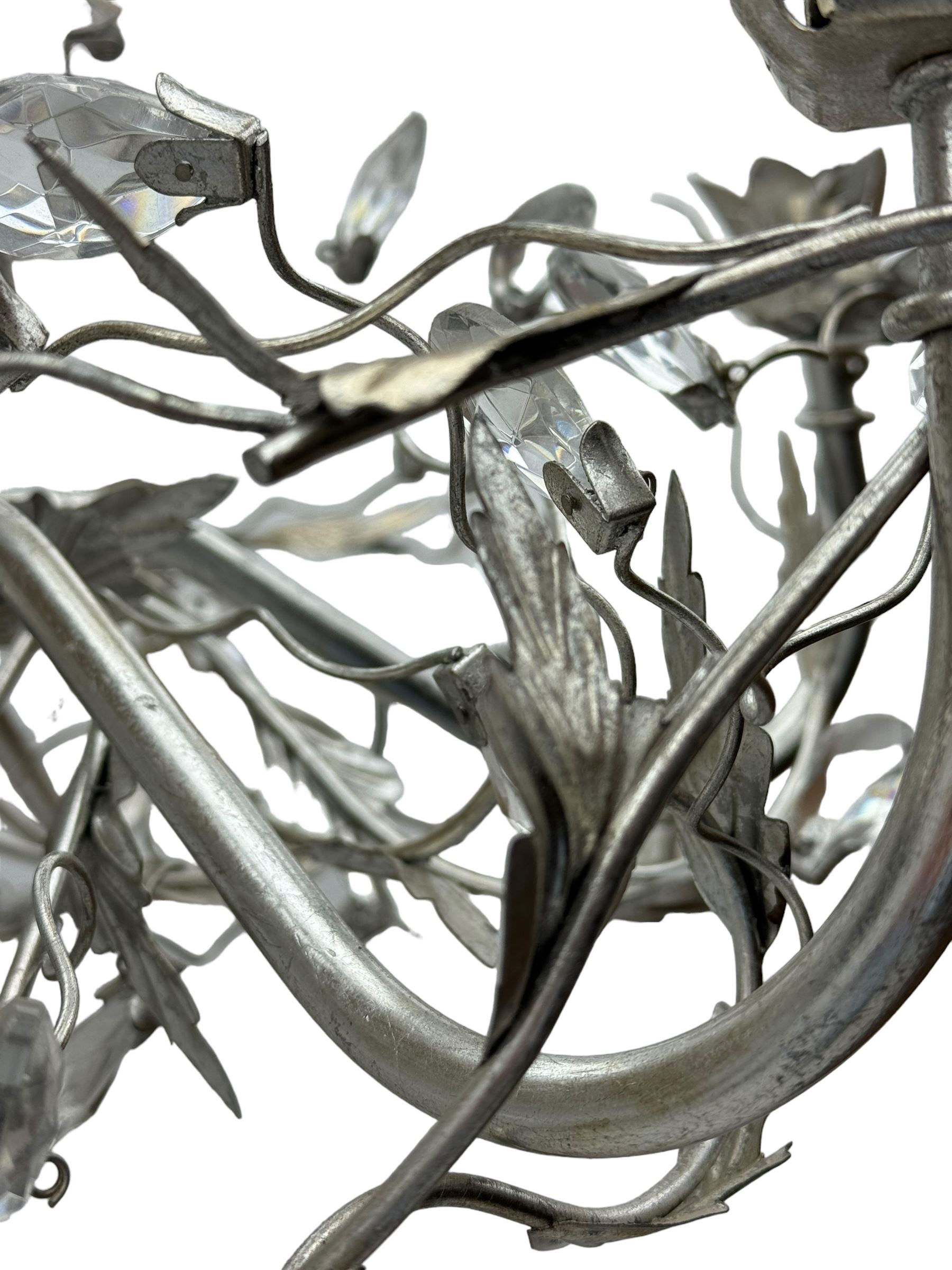 India Jane - silver finish metal chandelier, modelled with scrolling vines and leaves, embellished with faceted glass drops, fitted with six candle sconces, and wired for electricity