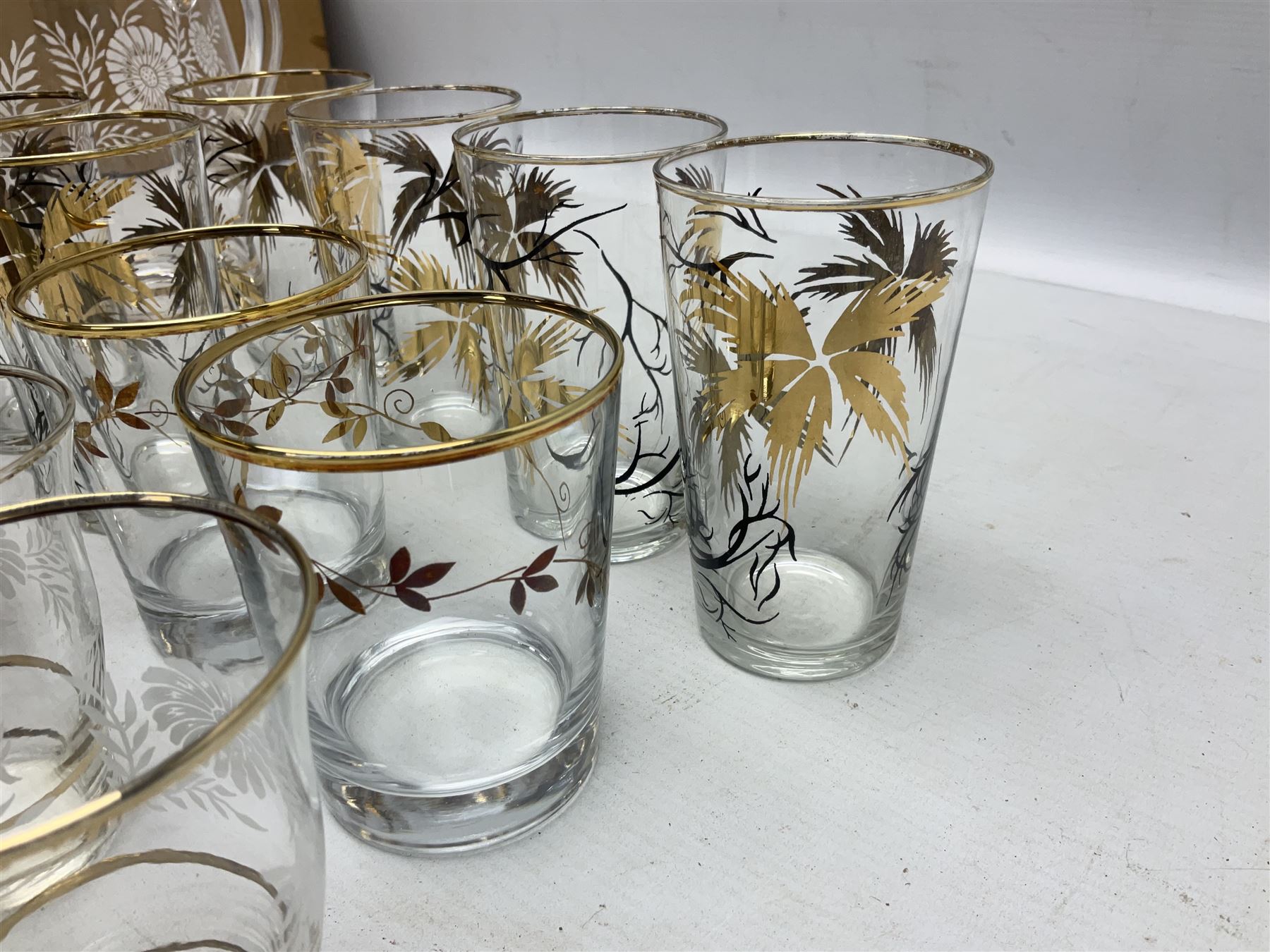Mid 20th century glass part lemonade set comprisimg jug decorated with white floral sprays and gilt banding with three matching cups, together with a set of six tumblers decorated in black and gilt with flowers and set of four other glasses