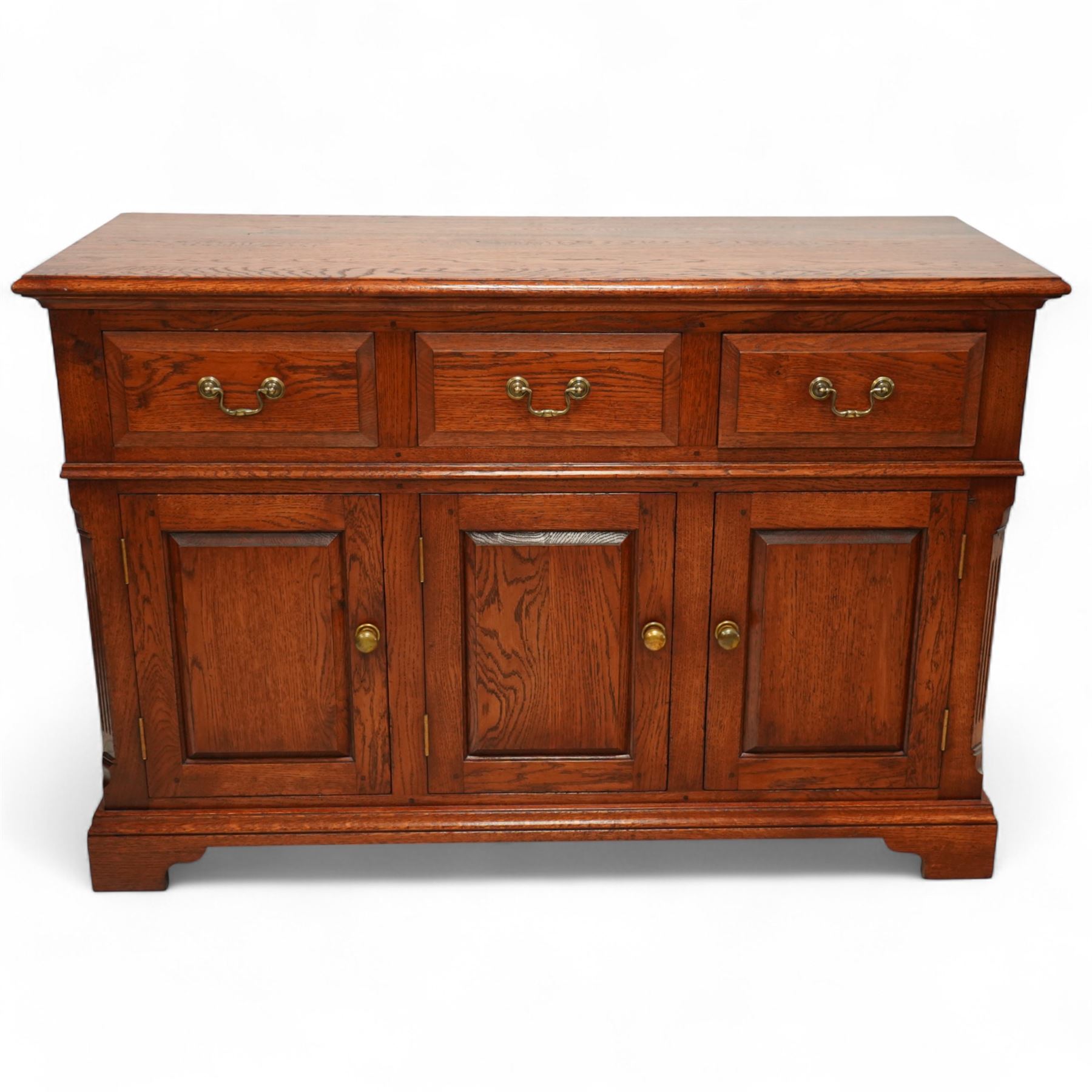 20th-century oak side cabinet, rectangular top above an arrangement of three drawers and three panelled cupboard doors, fitted with brass knobs, raised on bracket feet  