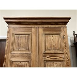 Victorian pitch pine double wardrobe, projecting moulded cornice over two panelled doors, the interior fitted with hanging rail and hooks, single drawer to base