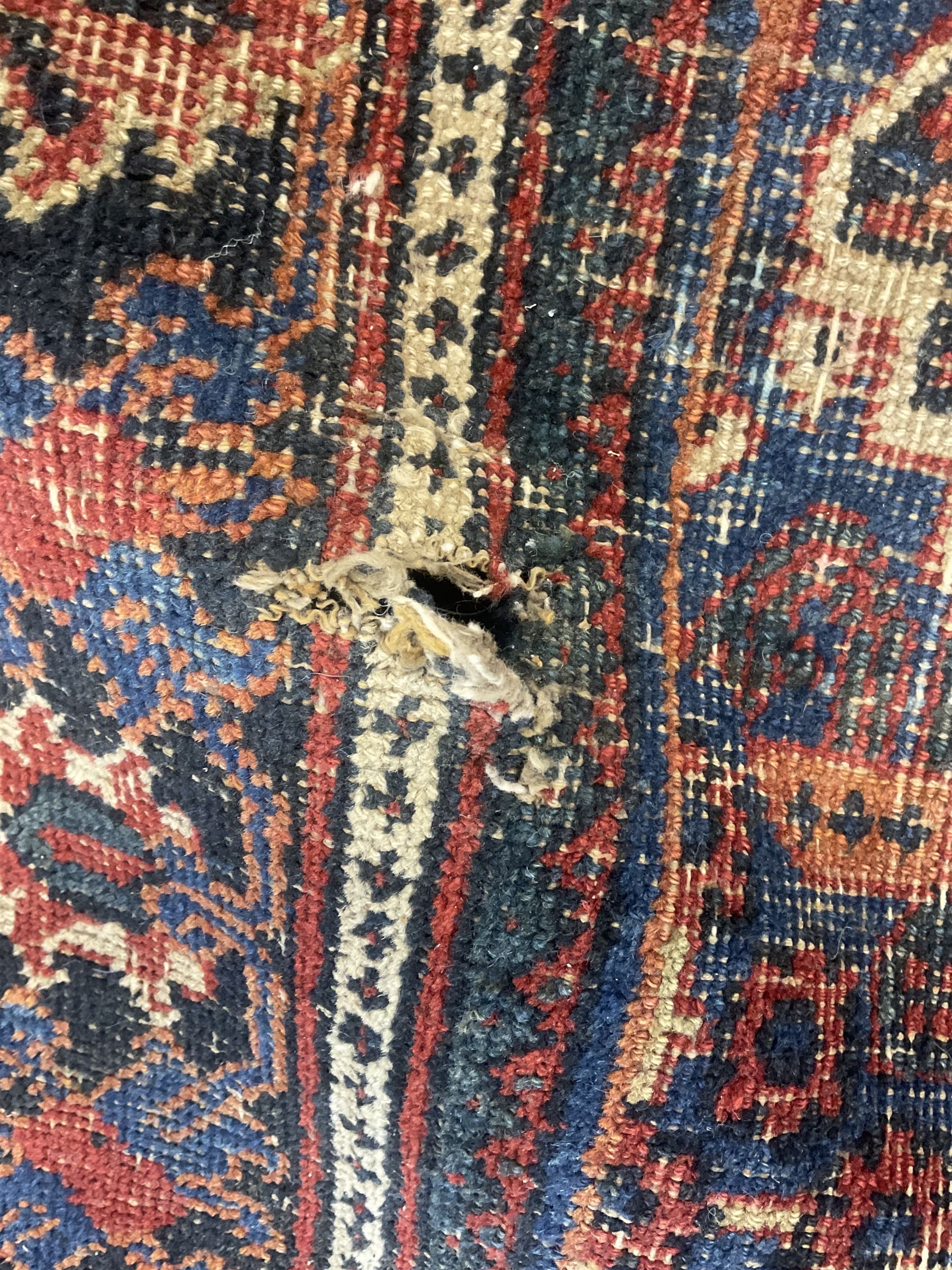 Persian Hamadan red ground rug, the field decorated with floral motifs with central lozenge medallion, guarded border decorated with repeating stylised plant motifs