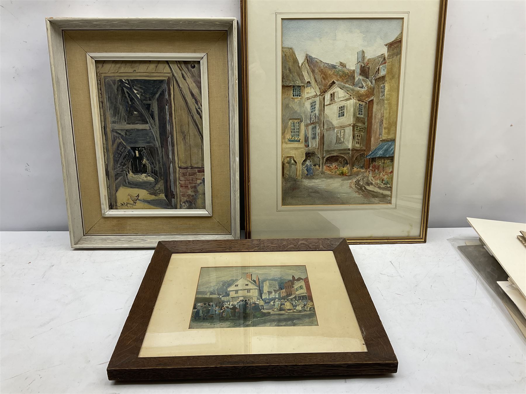 Marjorie Holland (British early 20th century): 'Interior of an Old Barn - Little Norton', watercolour signed, titled verso 30cm x 20cm; English School (early 20th century): Street Scene, watercolour unsigned 36cm x 23cm; Continental School (19th/20th century): 19th Century Market Scene, watercolour signed with initials JMC 17cm x 19cm (3)