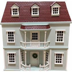 Wooden double fronted three-storey dolls house with pale blue stucco finish and simulated tiled roof, the central recessed front door with balustraded veranda and balcony above, single hinged front opening to reveal four fully decorated rooms and attic room with hinged roof access, fully furnished with quality wooden furniture and comprehensive range of accessories, and seven family member dolls H75cm W64cm D40cm; with oak finish two-tier stand (2)