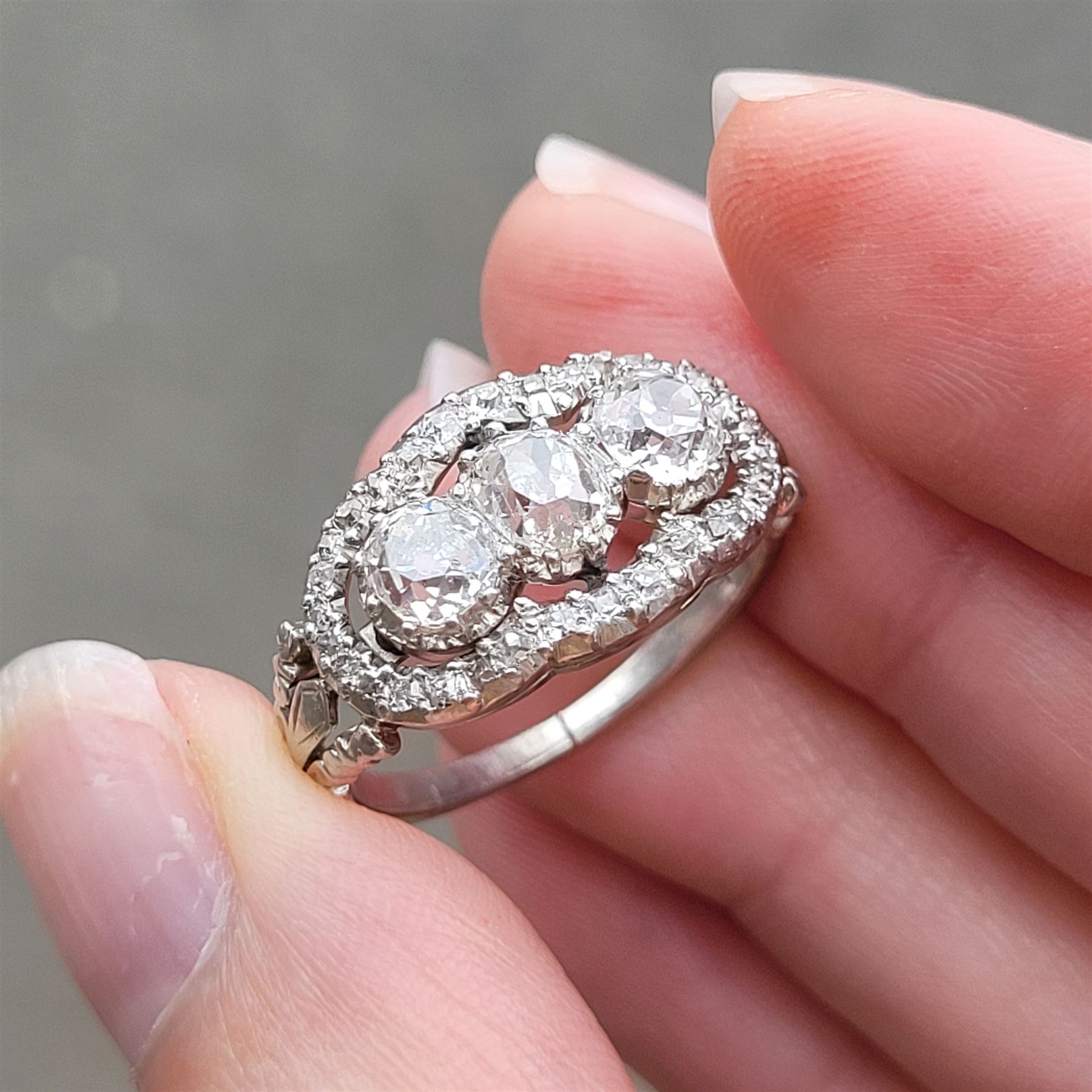 Late 19th / early 20th century platinum diamond ring, three old cut diamonds, in an openwork setting surrounded by further old cut diamonds, with pierced design shoulders, principal three diamonds total weight approx 1.45 carat, in a velvet and silk lined box by Selfridges