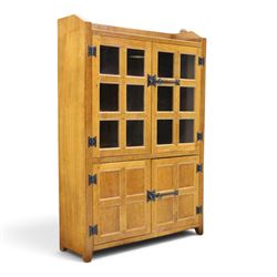 Rabbitman - oak glazed bookcase or display cabinet, lightly adzed rectangular top with raised gallery, twin glazed doors enclosing two shelves, over a pair of panelled cabinet doors with wrought iron fittings, with carved rabbit signature, by Peter Heap of Wetwang