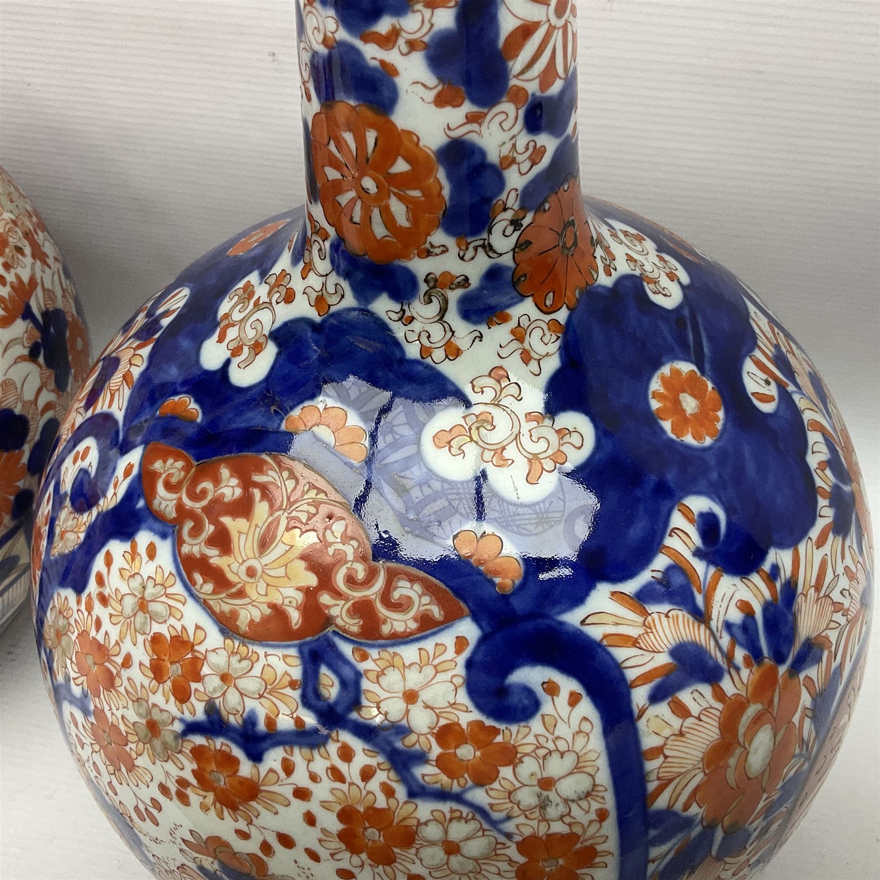 Pair of large 19th century Japanese Imari porcelain bottle vases, painted with shaped reserves of peonies, chrysanthemums and prunus blossom, each H46cm