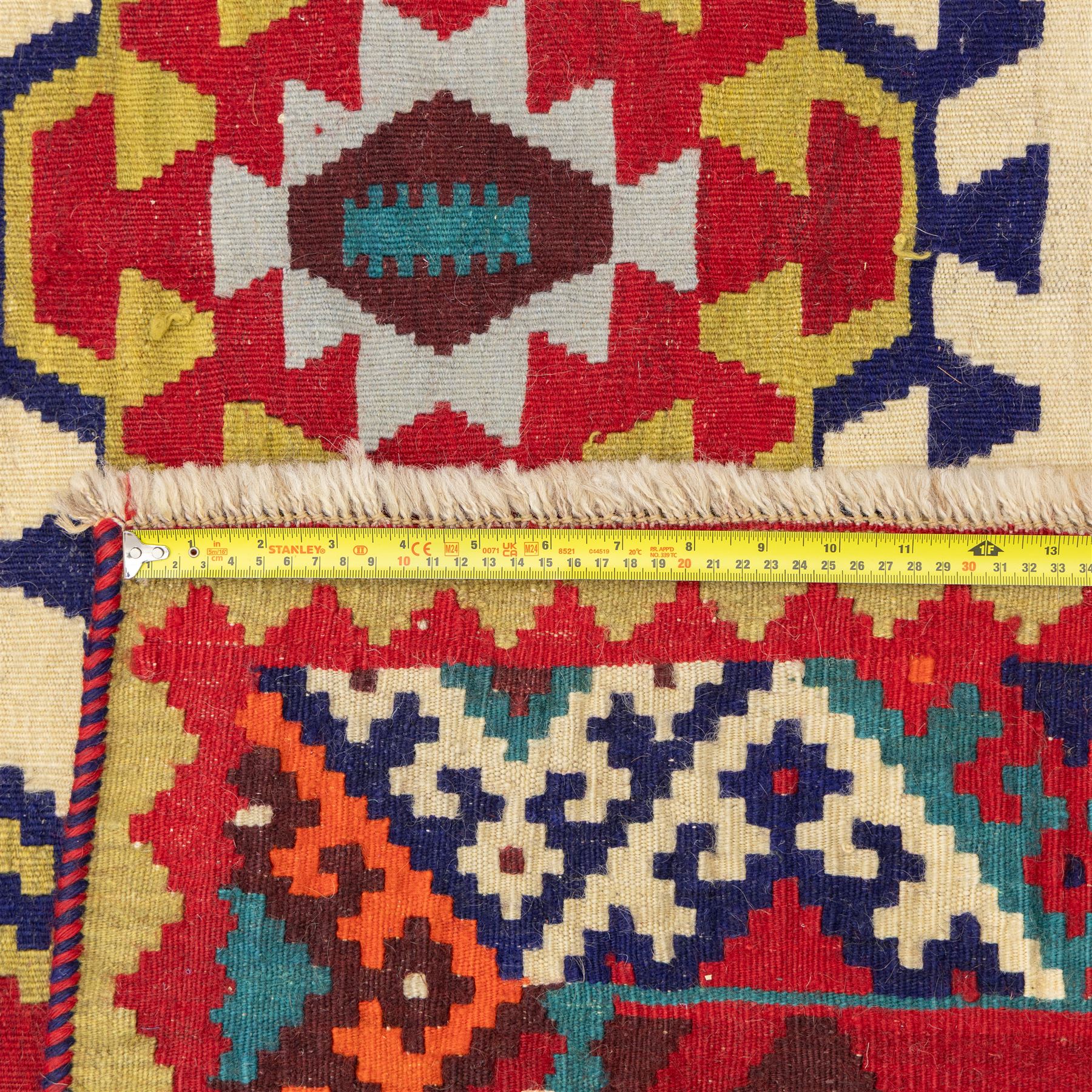 South west Persian Qashqai flatweave kilim, central field with a linked column of hooked diamond medallions in polychrome tones with an ivory lattice on a magenta ground framed by multiple geometric borders 