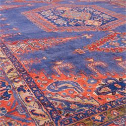 Central Persian Veis hand-knotted carpet, deep blue indigo field with central stepped lozenge medallion filled with stylized floral and geometric motifs, flanked by further angular medallions and tribal devices, edges with articulated and serrated hooked forms within a wide geometric border with repeating stylized floral motifs and multiple guard borders, in madder red, indigo blue, ivory, olive green, with cotton fringe ends