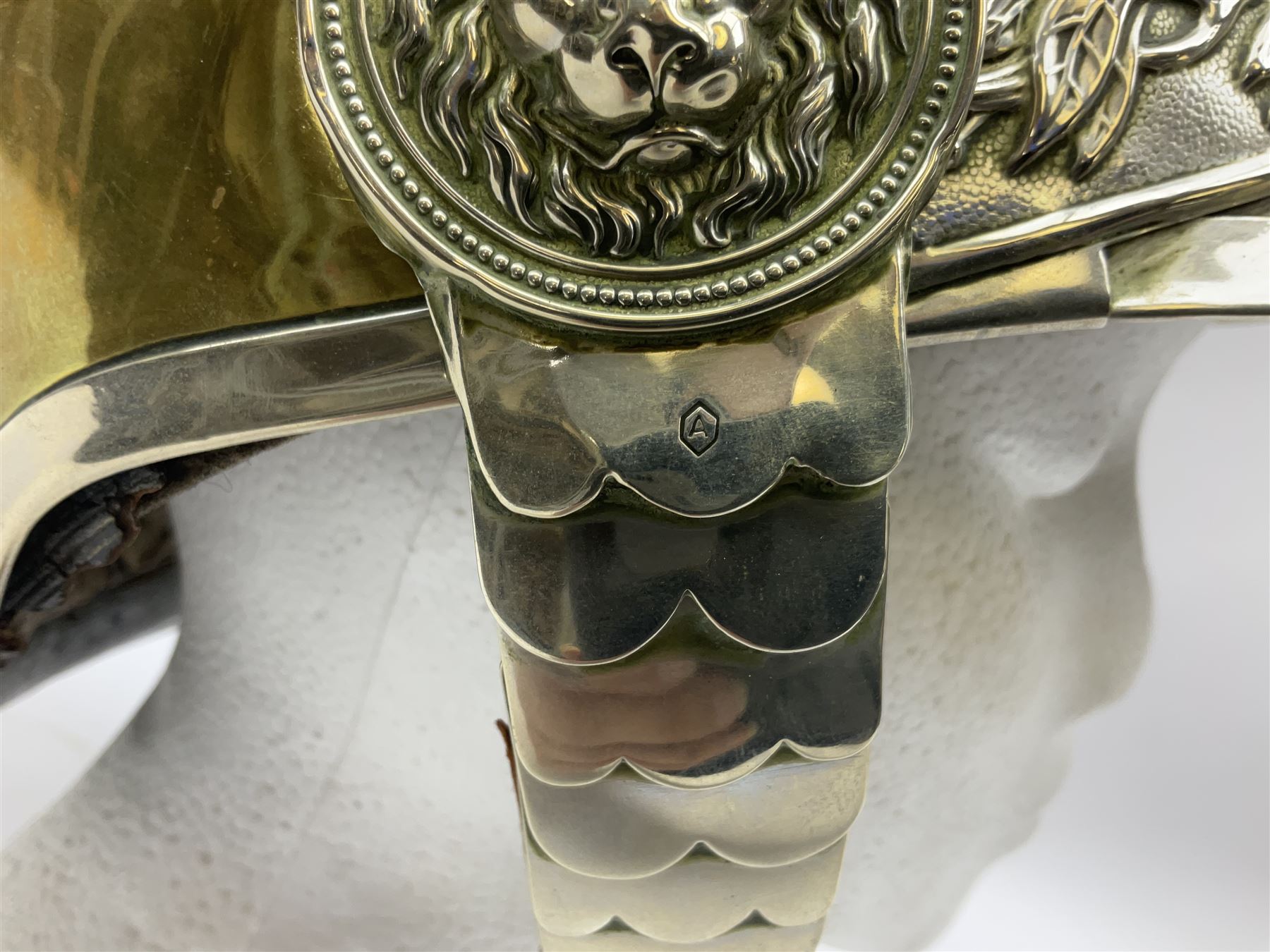 Early 20th century French mounted gendarme's helmet, brass with nickel-silver mountings, broad band embossed with fused grenade, high comb with the face of the gorgon Medusa at the peak and with a black horse hair crest, plume socket at the left, leather-backed nickel-silver chin scales with lion mask mounts.