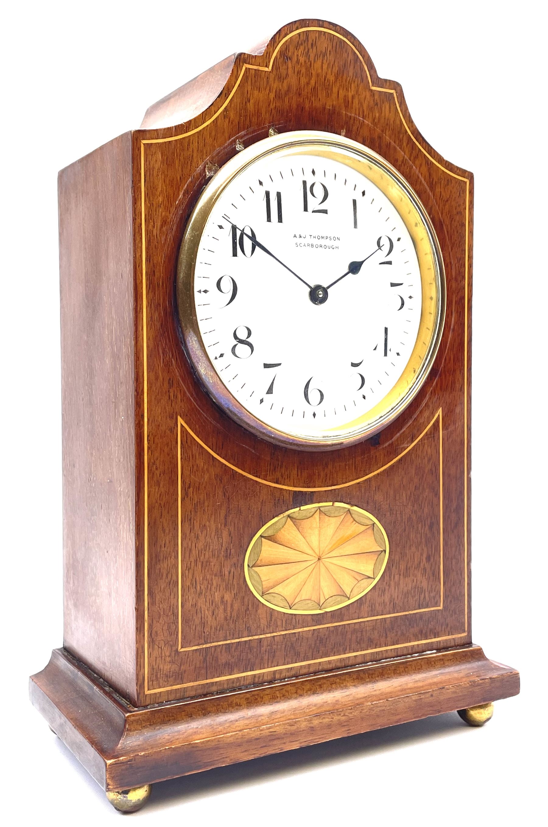 Edwardian inlaid mahogany mantel clock, stepped cavetto and arched top pediment, circular white enamel Roman dial signed 'A & J. Thompson, Scarborough', the front inlaid with fan motif, raised on globular brass feet, single train driven movement by 'R & Co. Paris'