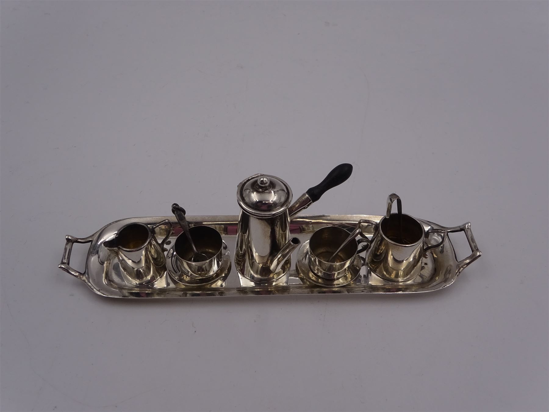 Edwardian miniature silver tea set, comprising hot chocolate pot, two cups and saucers, milk jug, sugar bowl and tray, hallmarked Cornelius Desormeaux Saunders & James Francis Hollings (Frank) Shepherd, Chester & Birmingham 1908, with two spoons and pair sugar tongs, hot water pot H3.8cm