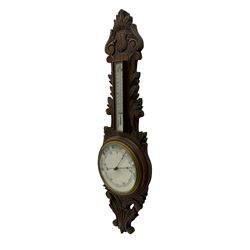A 1920s oak cased patented aneroid barometer with openwork decorative carving, 8” enamel dial recording air pressure from 26 to 32 inches with weather predictions in gothic script, steel indicating hand and brass recording hand within a brass bezel and flat glass (glass cracked), with a boxed mercury thermometer recording the temperature in degrees centigrade and Fahrenheit.    

