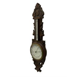 A 1920s oak cased patented aneroid barometer with openwork decorative carving, 8” enamel dial recording air pressure from 26 to 32 inches with weather predictions in gothic script, steel indicating hand and brass recording hand within a brass bezel and flat glass (glass cracked), with a boxed mercury thermometer recording the temperature in degrees centigrade and Fahrenheit.    

