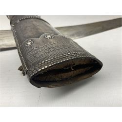 Late 19th/20th century Middle Eastern jambiya dagger the 36cm broad curved double edged steel blade with traces of script, horn and copper backed waisted white metal hilt with three roundel buttons; in ornate white metal and leather mounted brass and steel scabbard L60.5cm overall