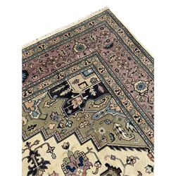 Persian Heriz pale olive and ivory ground carpet, large quatrefoil medallion with palmettes, the surrounding field decorated with trailing leafy branches and stylised plant motifs, peach ground borders with overall floral pattern, within guard stripes 