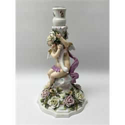 A late 19th century Sitzendorf figural candlestick, modelled as a putto supporting a socket with swan head terminal, the spreading base heavily encrusted with flowers, with printed mark beneath, H32cm.