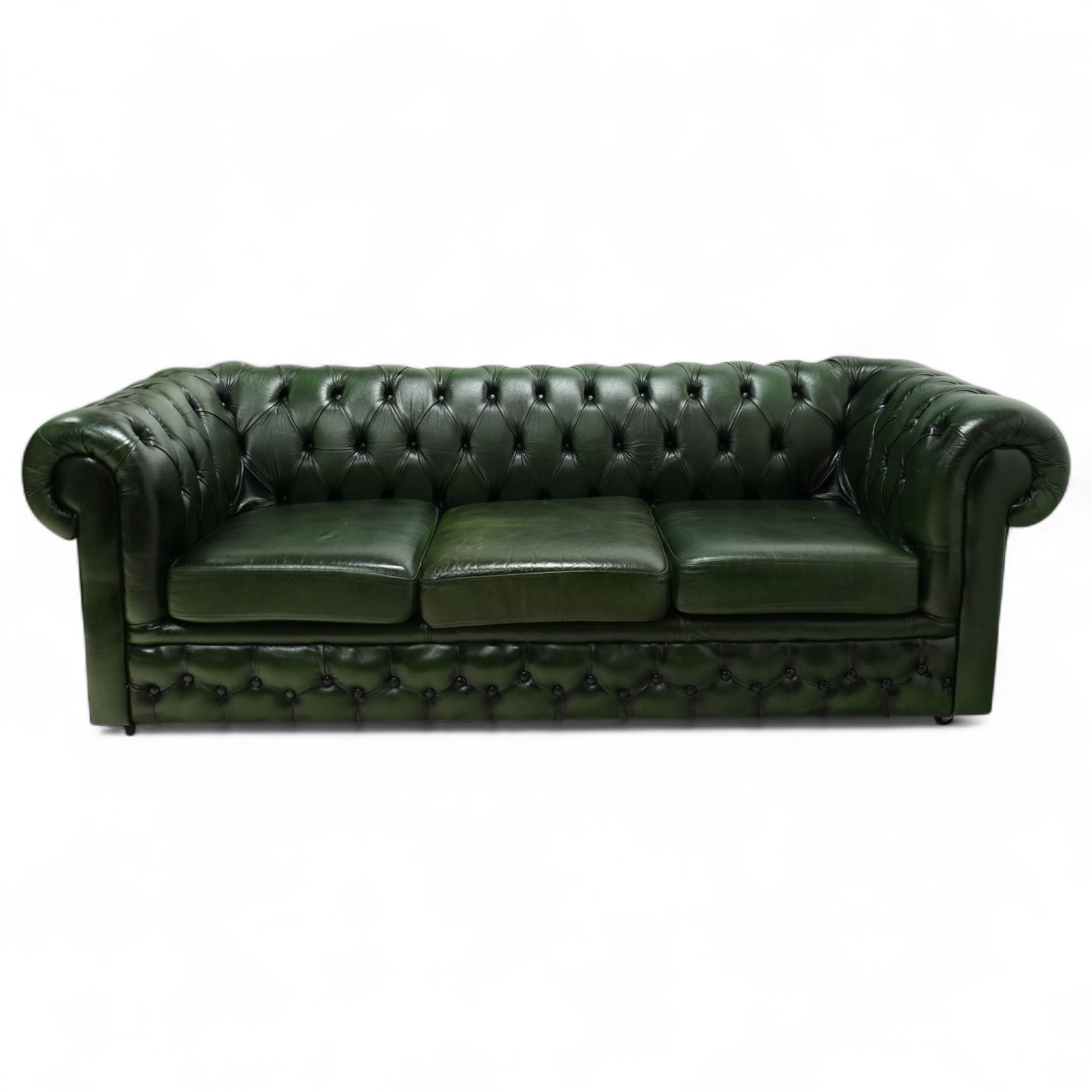 Late 20th century chesterfield style sofa upholstered in green leather, with deep buttoned back and arms above three loose cushions, continuous scroll arms and front, on concealed block feet