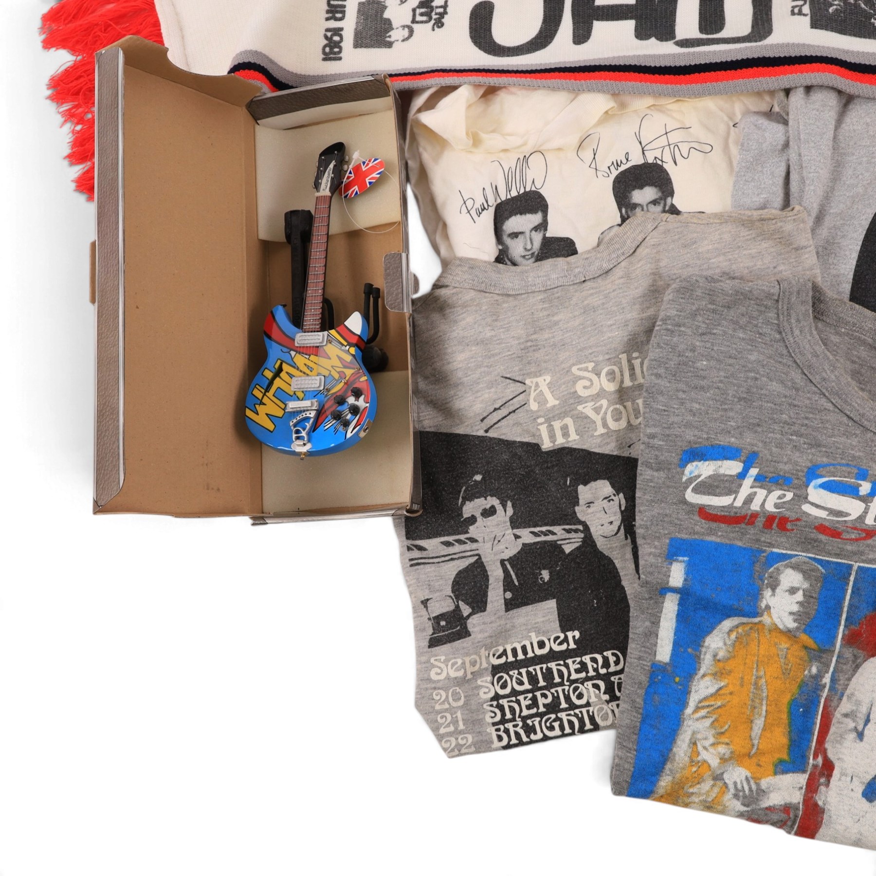 Five 1980s The Jam/Paul Weller/The Style Council tour/band t-shirts, including Cafe Bleu, The Paul Weller Movement, Dig The New Breed, A Solid Bond in Your Heart and Beat Surrender Tour 1982, together with a 1981 The Jam tour scarf and a Baby Axe Company miniature model of Paul Weller's Rickenbacker guitar