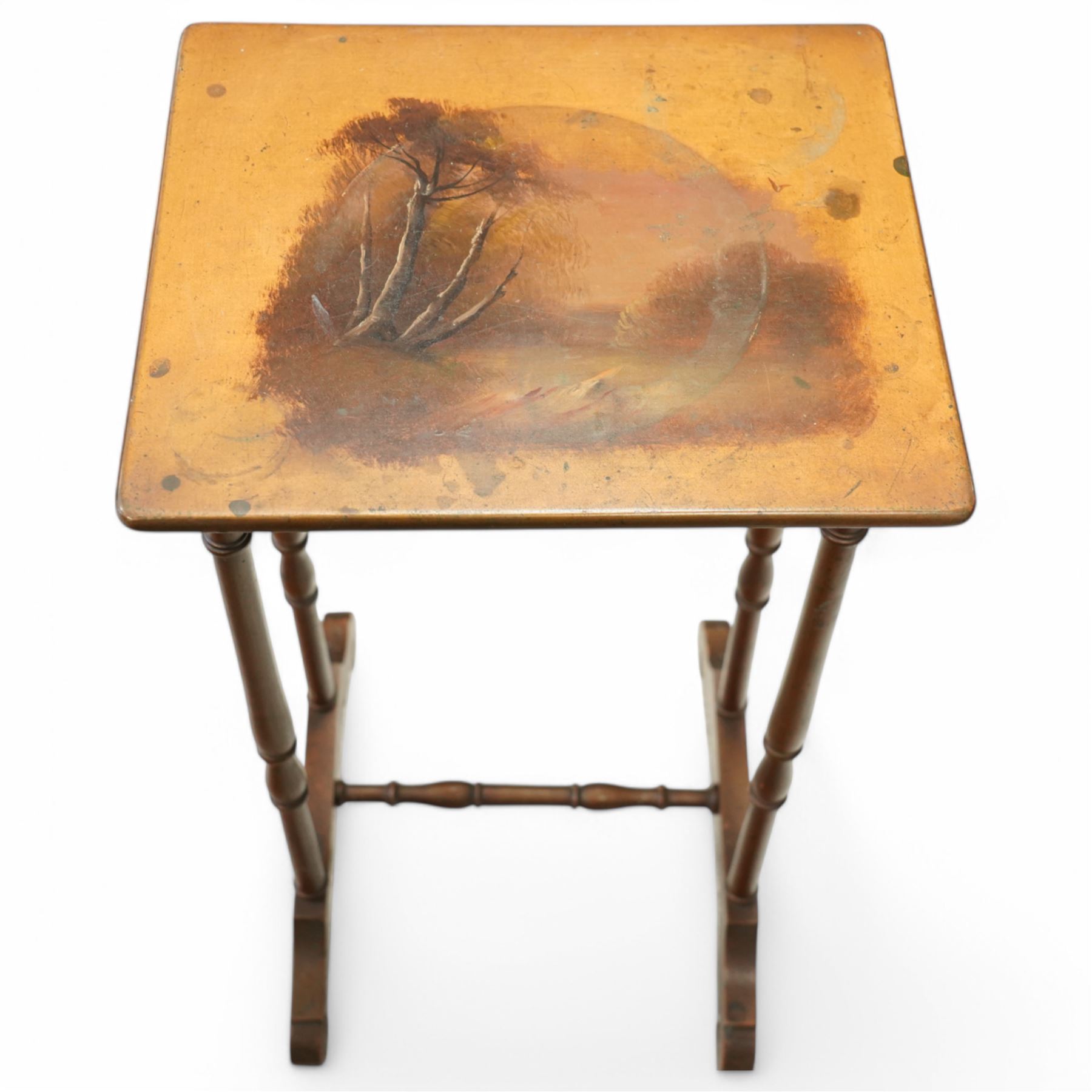 French 19th century painted nest of tables, the largest depicting a romantic scene of courting lovers by a swan lake, indistinctly signed L Desi**, the smaller tables painted with rural landscapes, the painted rectangular tops raised on ring turned end supports united by stretcher