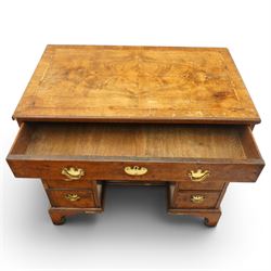 George II figured walnut kneehole desk, the rectangular book-matched veneer top with feather and cross-banding, fitted with single frieze drawer over a short drawer and central recessed cupboard, flanked by three drawers to each side, lower moulded edge on bracket feet