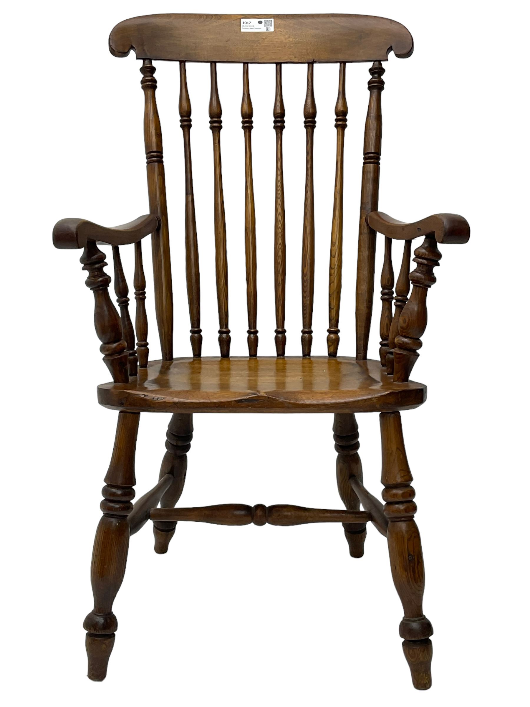 Early 19th century elm farmhouse armchair, the shaped eared cresting rail over tall spindle back, dished seat on turned supports united by H stretchers