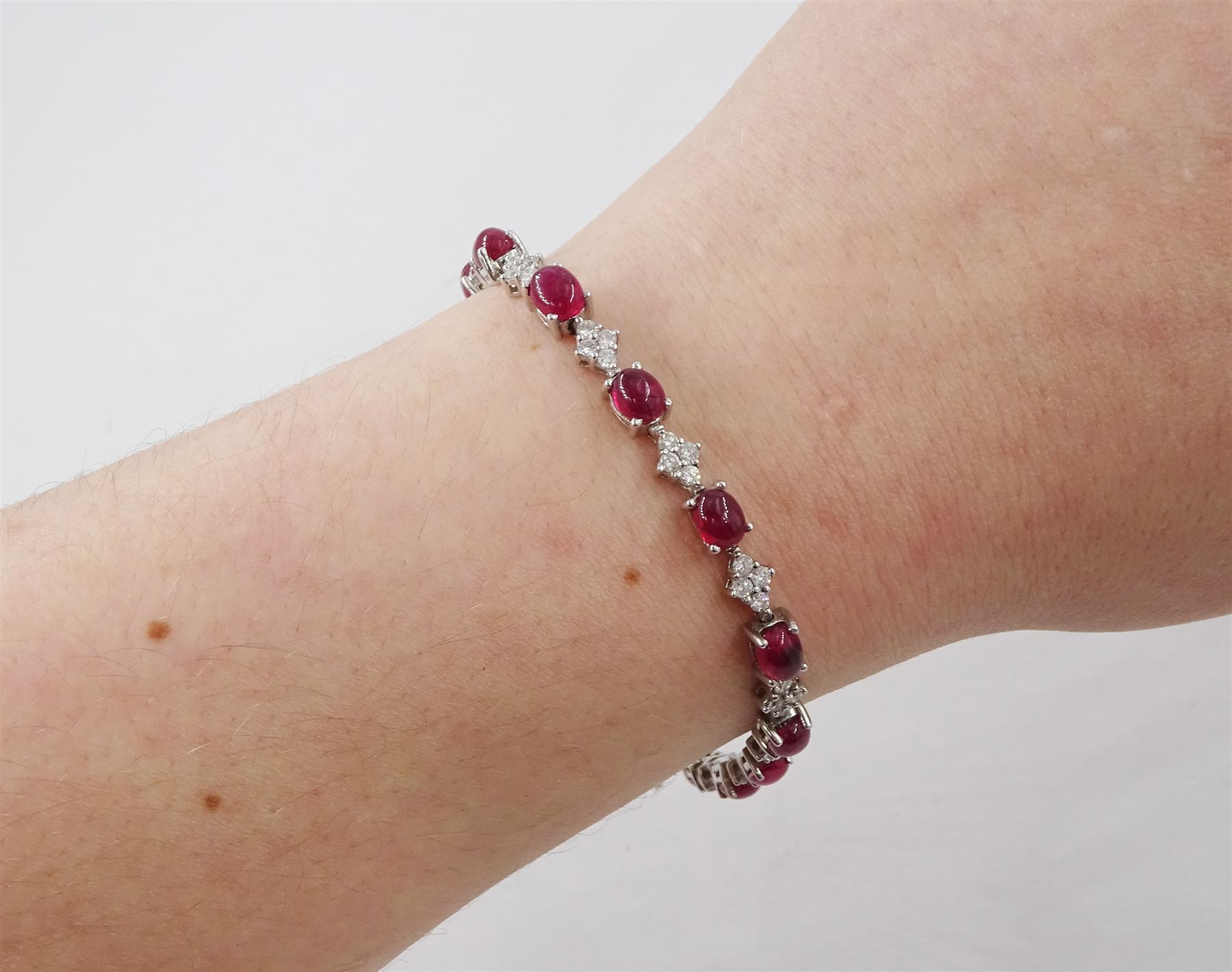 18ct white gold ruby and diamond bracelet, fifteen oval cabochon cut rubies, each spaced by four round brilliant cut diamonds, Sheffield 2009, total ruby weight 10.10 carat, total diamond weight approx 0.60 carat