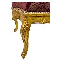Pair of Louis XV-design giltwood stools, each upholstered in red damask fabric with slight variations in patterns, the carved frames adorned with scrolling foliage and shell motifs, raised on cabriole supports