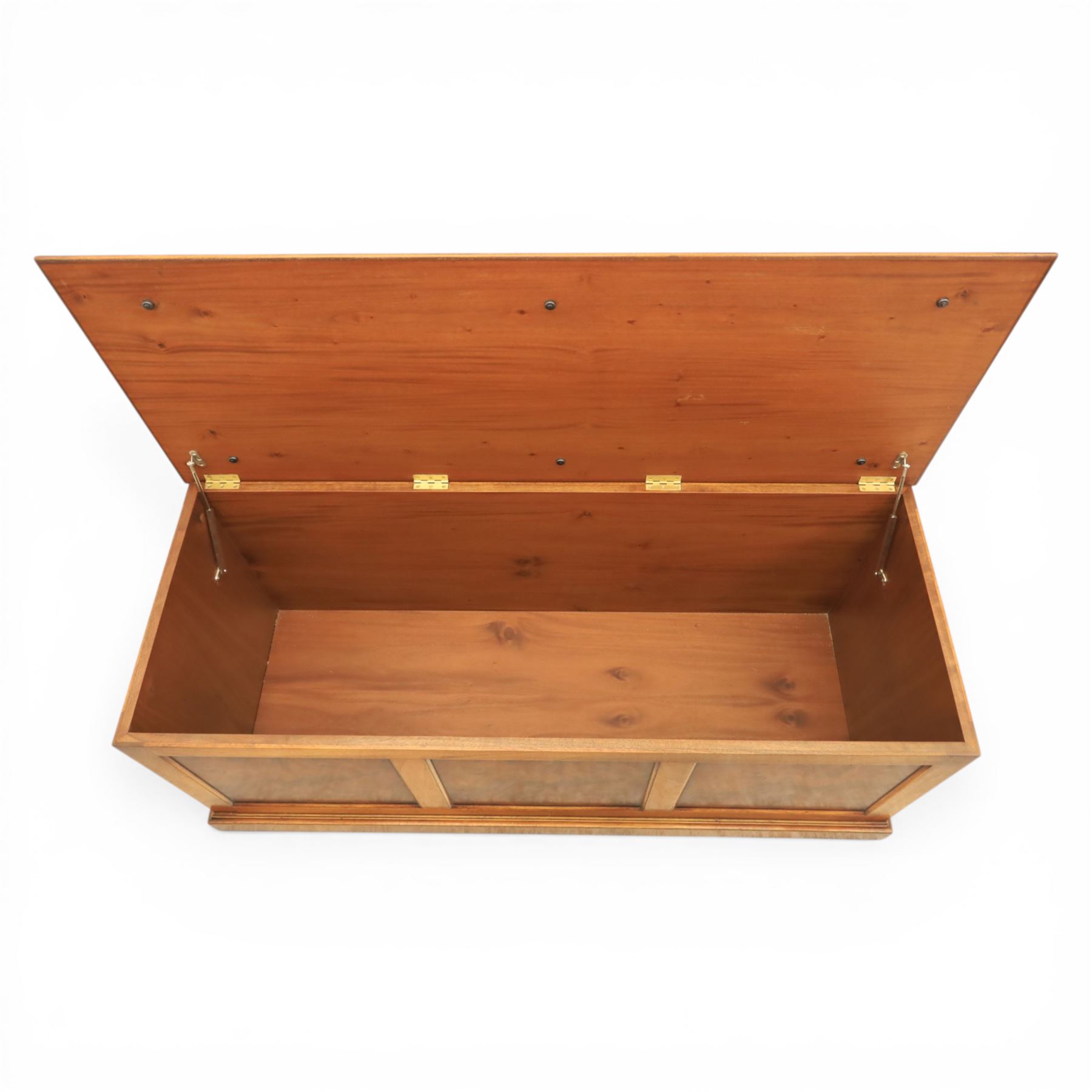 Traditional design figured elm blanket chest, with padded striped upholstered seat, over a hinged top with panelled sections below raised on a plinth base