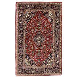 Persian crimson ground rug, the central indigo pole medallion within a field decorated with palmettes and floral patterns with contrasting spandrels, guarded border with repeating rinceaux patterns