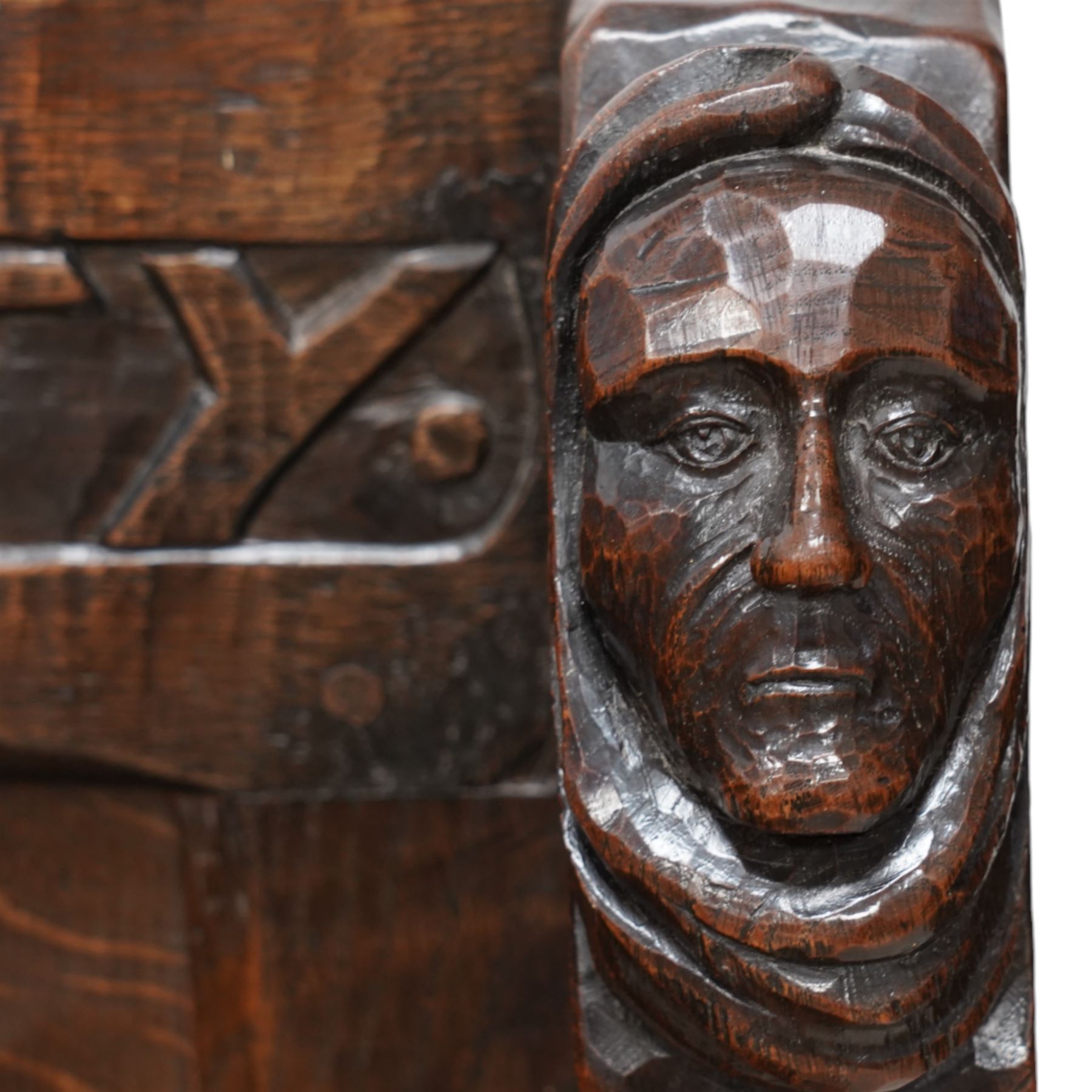 Mouseman - circa. 1920s adzed oak settle or bench, the cresting rail carved with inscription 'Before Honour is Humility', four panel back and plank seat on shaped end supports carved with grotesque masks terminals, carved with mouse signature, by Robert Thompson of Kilburn 
