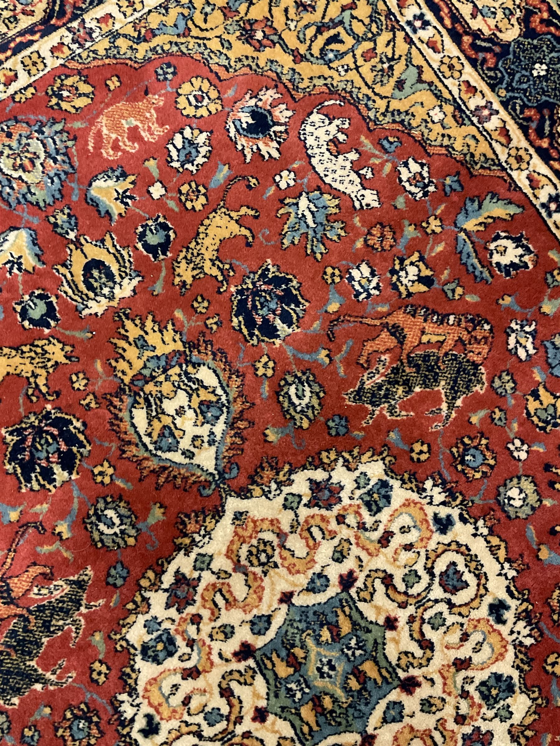 Persian design red ground rug, decorated with plant and animal motifs, the border decorated with floral design panels with guards
