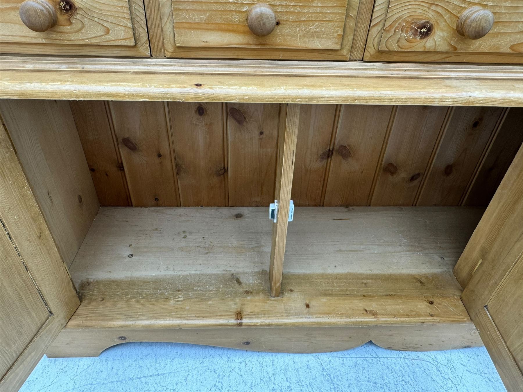 Early 20th century pine kitchen dresser, featuring a hutch with arched top over three open shelves, the base with five drawers over three cupboard doors, turned column supports flanking the doors, scalloped apron base with bracket feet