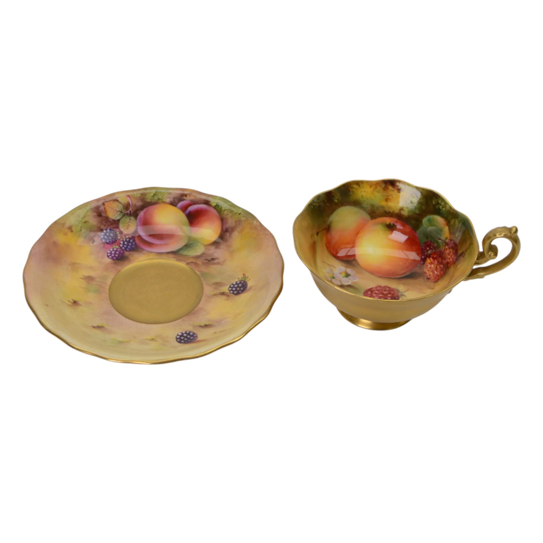 Royal Worcester fruit painted cabinet teacup and saucer, interior hand painted with apples, blackberry and cherries upon a mossy ground, the cup exterior and centre of saucer gilded, cup and saucer signed Rickells, each with puce coloured printed marks beneath, H7cm