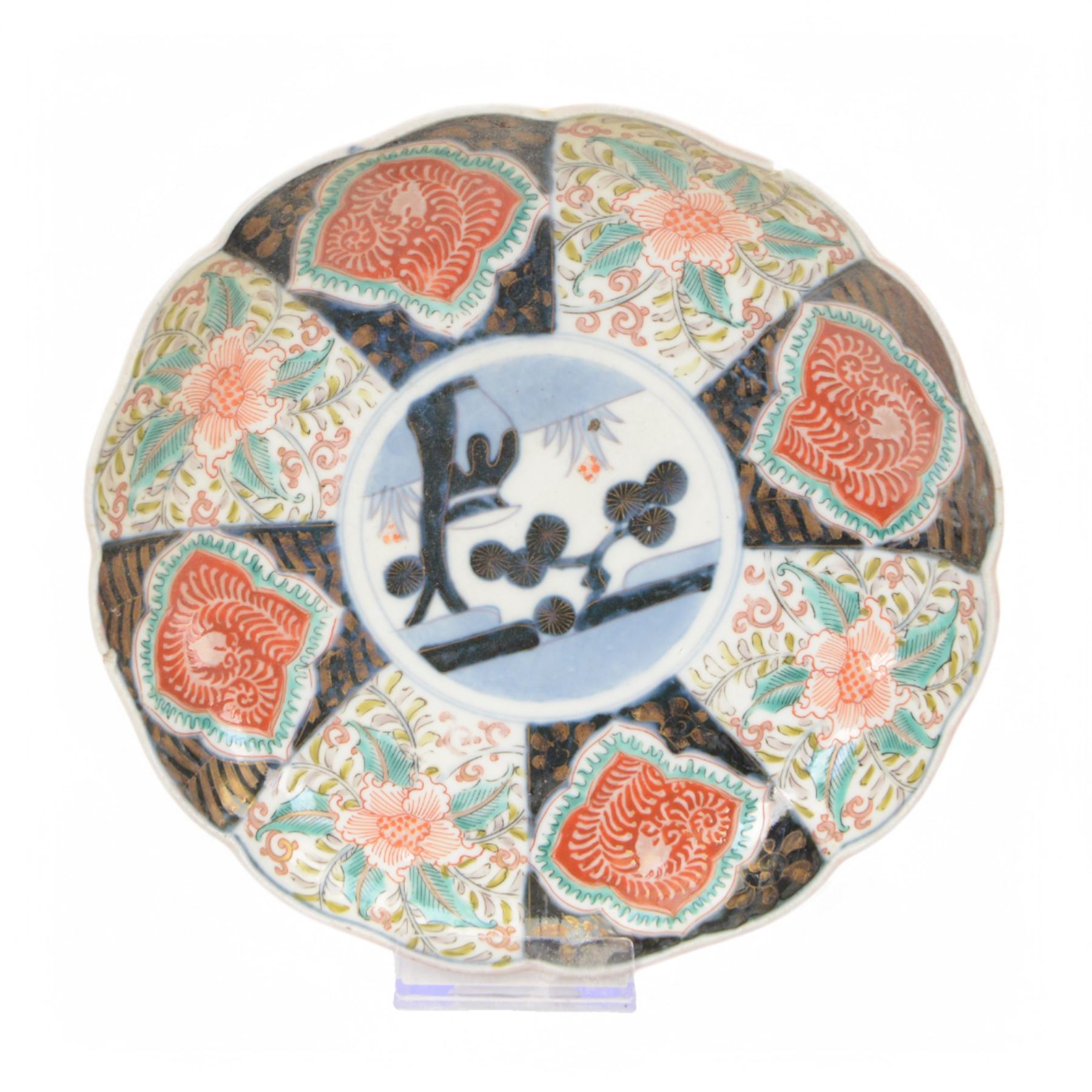 Group of 19th century Japanese Imari porcelain, Meiji period, comprising pair of lobed dishes, decorated stylised reserves and painels in blue and gilt upon a red ground, H6.5cm D21.5cm, a pair of plates of circular lobed form, decorated with a central panel depicting a vase beneath pine branches, and surrounded by panels of flowers and stylised quatrefoil shapes, D21cm, and another similar example painted with a character in underglaze blue to the centre, with character mark beneath, D22cm, each with character marks beneath               