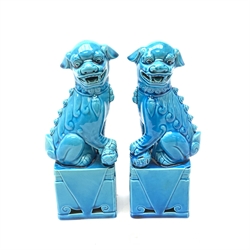 A pair of Chinese turquoise glazed temple dogs, each seated upon rectangular plinths, one resting their paw upon an 'embroidered' ball, the other upon a cub, H24cm. 