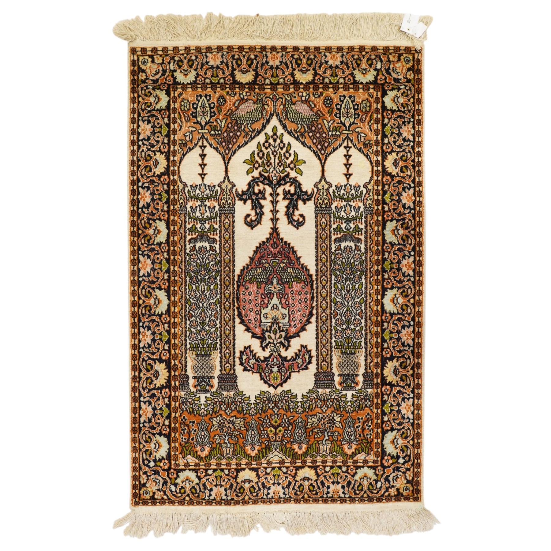Indian silk-inlaid prayer rug, ivory field decorated with a triple-arched Mirab motif, pendant medallion, paired birds and flowering vases, enclosed by a black ground guard band of scrolling foliage and palmettes