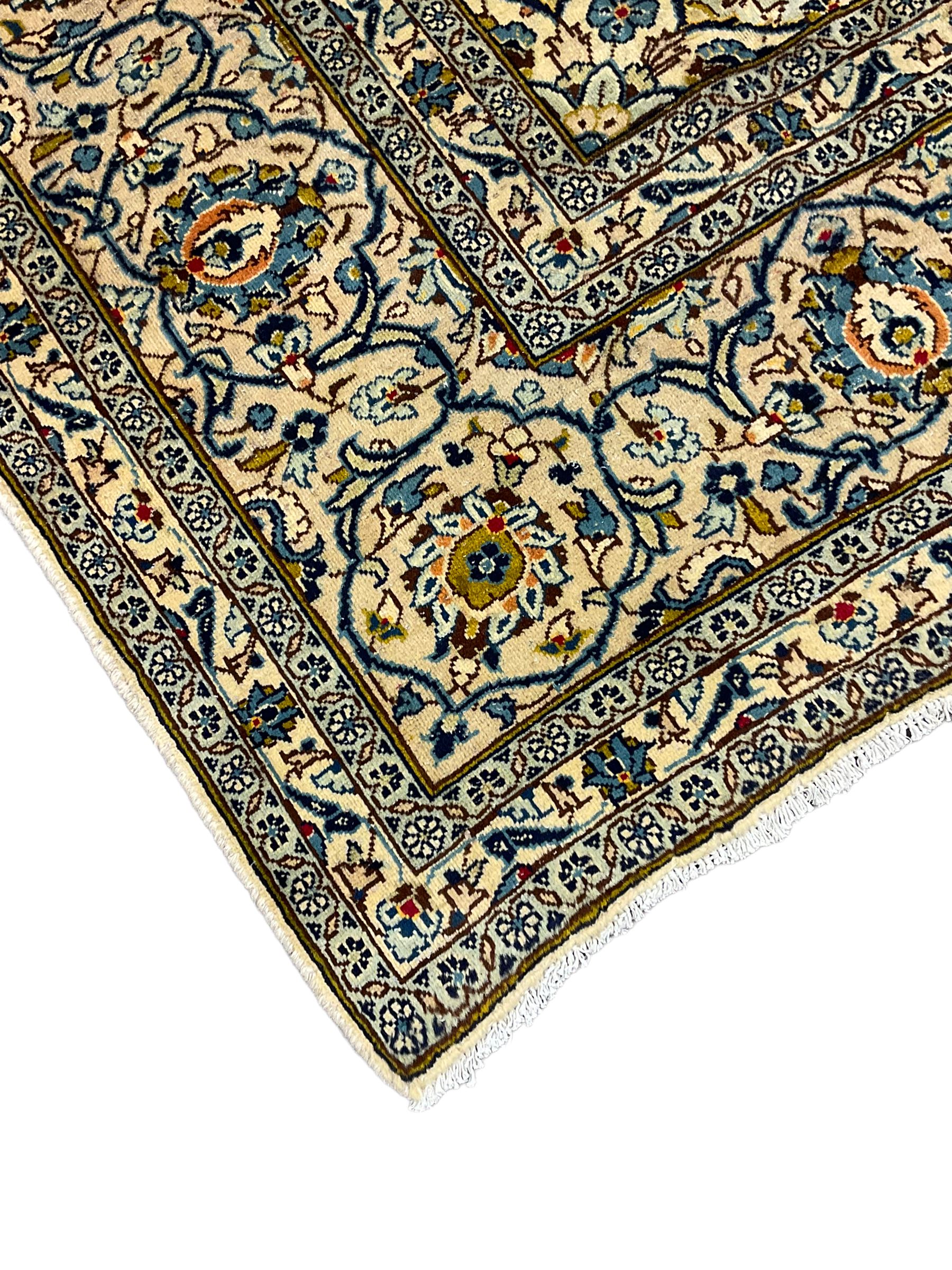 Persian Kashan golden ivory ground carpet, the central medallion surrounded by a field of interlacing branch and stylised plant motifs, the guarded border with scrolling design decorated with flower heads 