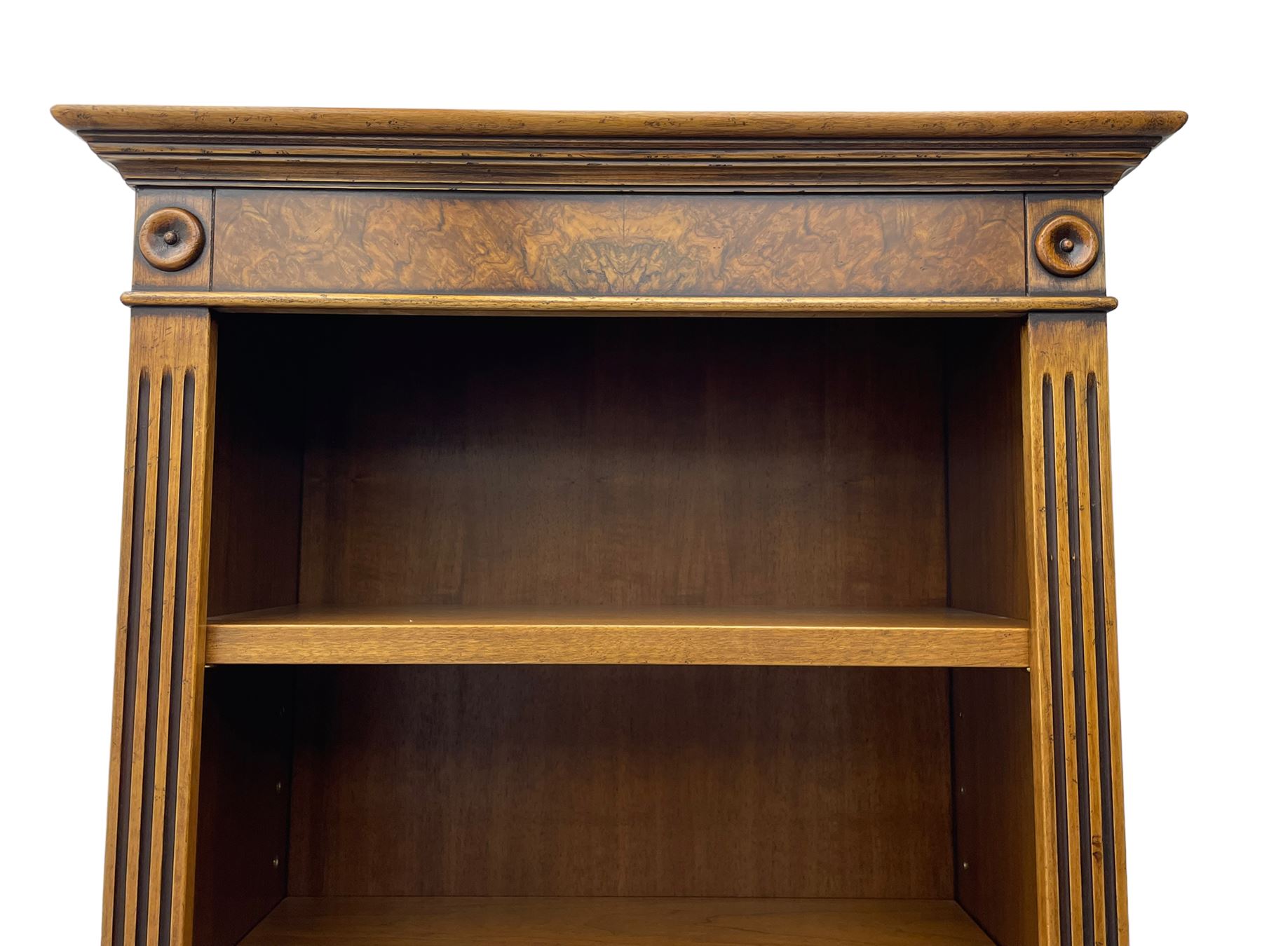 Georgian design walnut open bookcase, projecting cornice over figured banded frieze flanked by roundels, fitted with six adjustable shelves with flanking fluted uprights, on skirted base