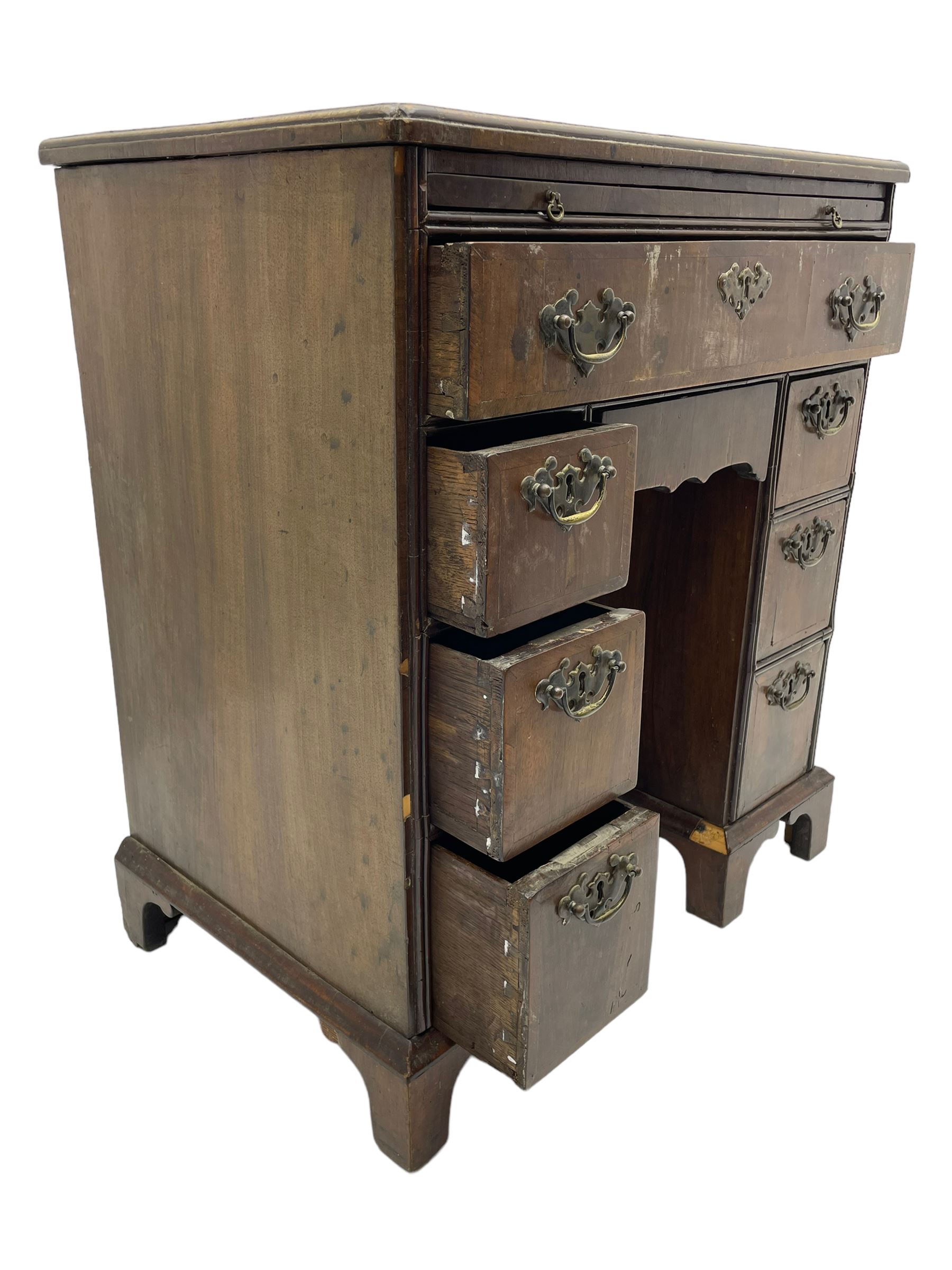 Georgian walnut kneehole desk, moulded rectangular top with book-matched veneers within crossbanding, fitted with slide over one long drawer, frieze drawer, six small drawers and recessed cupboard, raised on bracket feet