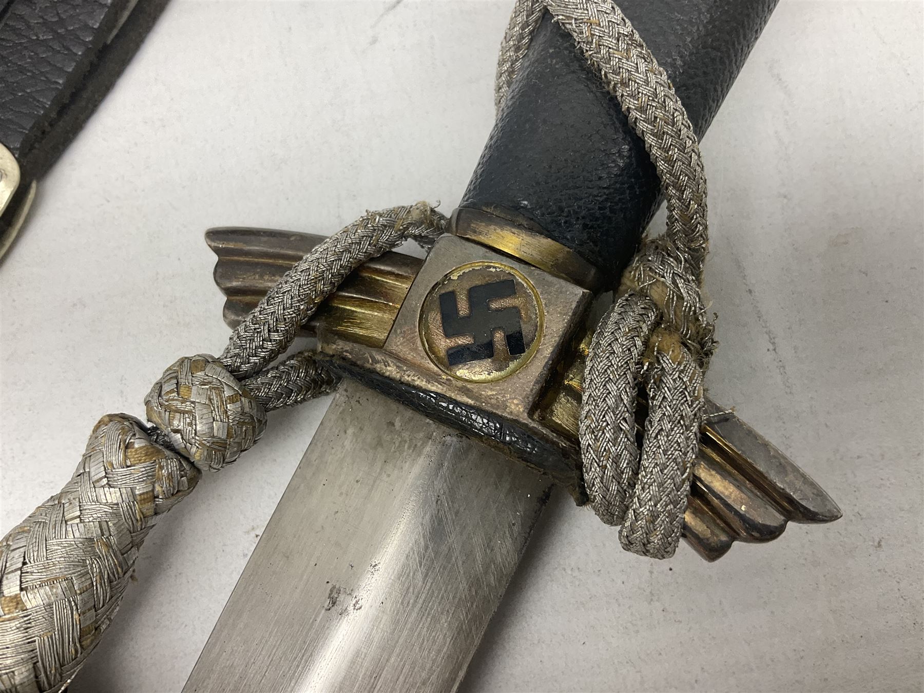 German Paul Weyersberg & Co Solingen DLV flyers dagger with 18cm steel blade, plated brass/tombac downswept cross-piece and pommel and leather covered grip, in leather and plated brass/tombac scabbard with leather hanger strap and silvered knot L35cm overall. Auctioneer's Note: After WWI Germany was forbidden an air force by the Treaty of Versailles however the Deutscher Luftsport-Verband (German Air-sport Association) was formed in March 1933 from various sports flying clubs and had branches for aeroplane, gliding and balloon flying. Under cover of the sporting DLV, many future Luftwaffe pilots trained to fly. DLV was embodied with the NSKK in March 1935 and on 1st March 1937 Luftwaffe was formed.