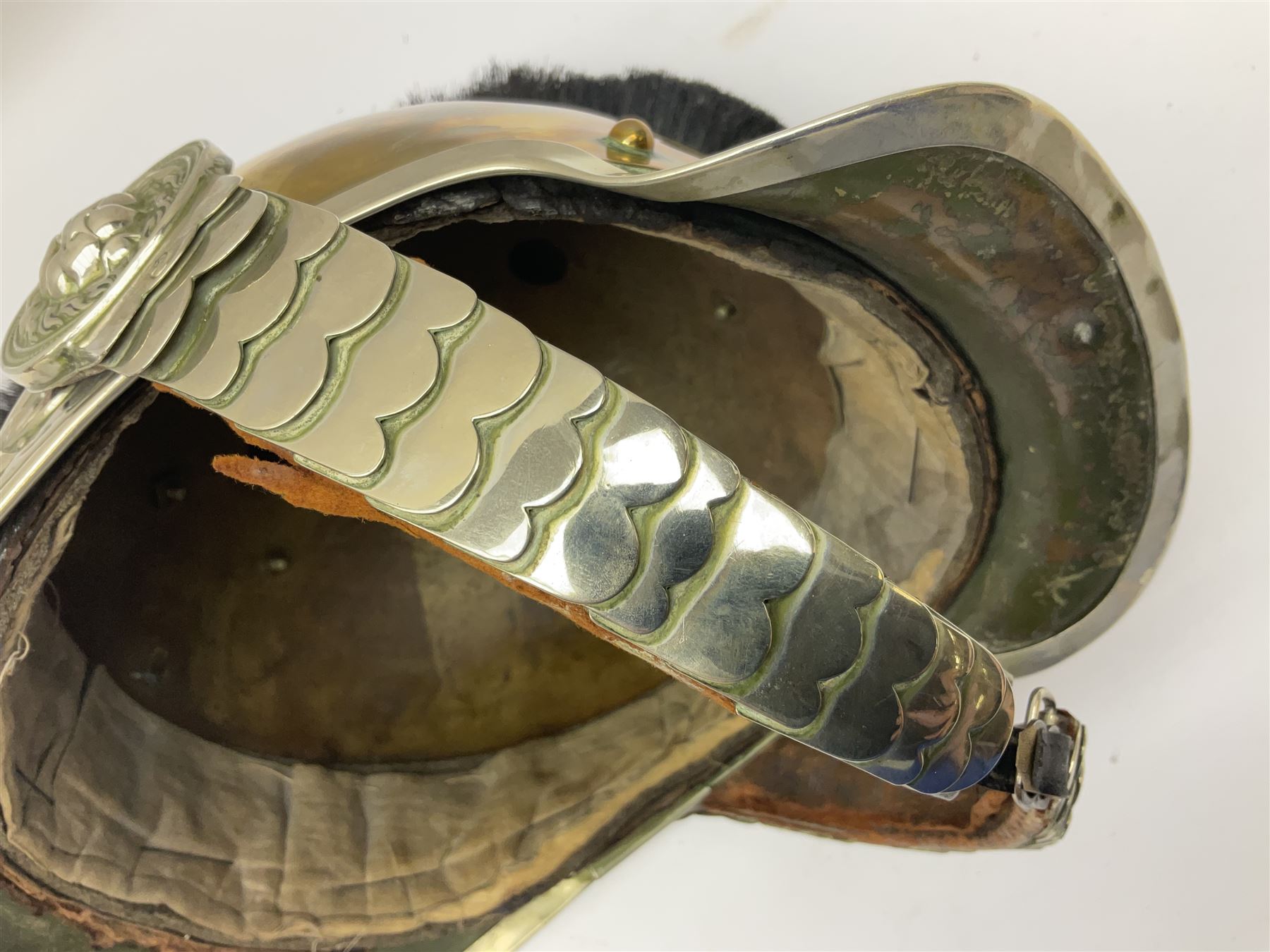 Early 20th century French mounted gendarme's helmet, brass with nickel-silver mountings, broad band embossed with fused grenade, high comb with the face of the gorgon Medusa at the peak and with a black horse hair crest, plume socket at the left, leather-backed nickel-silver chin scales with lion mask mounts.