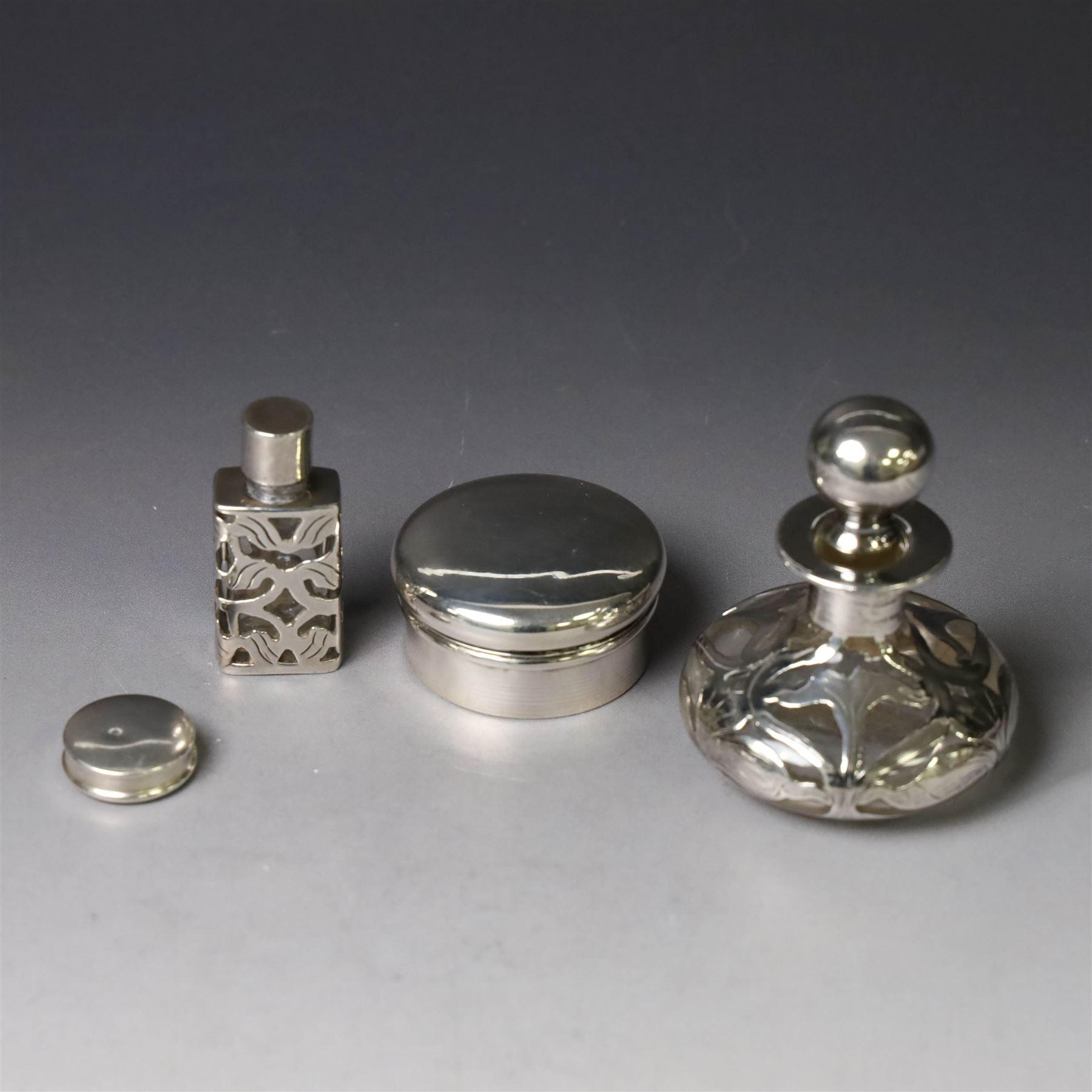 Two early 20th century silver pill/patch boxes, together with two glass perfume bottles with silver overlay and stoppers, all stamped or hallmarked, smallest box D2cm, largest bottle H7cm
